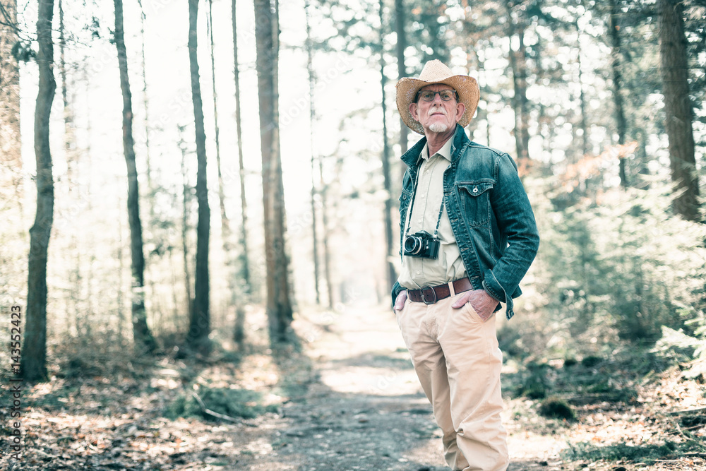Photographer wearing straw hat and jeans jacket in sunny forest. Photographer wearing straw hat and jeans jacket in sunny forest.