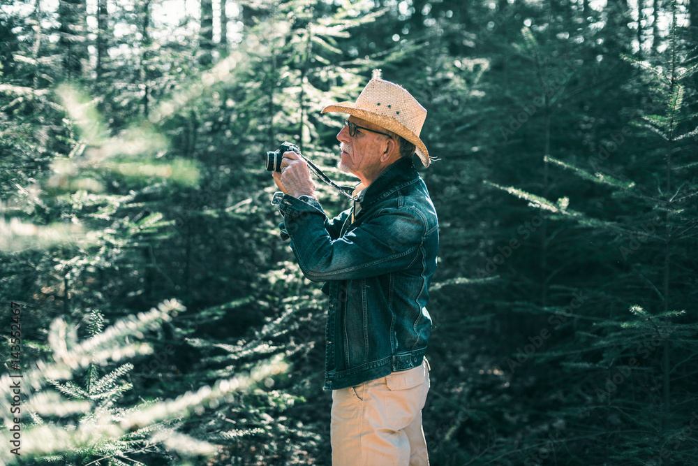 Senior male tourist with camera in forest. Senior male tourist with camera in forest.