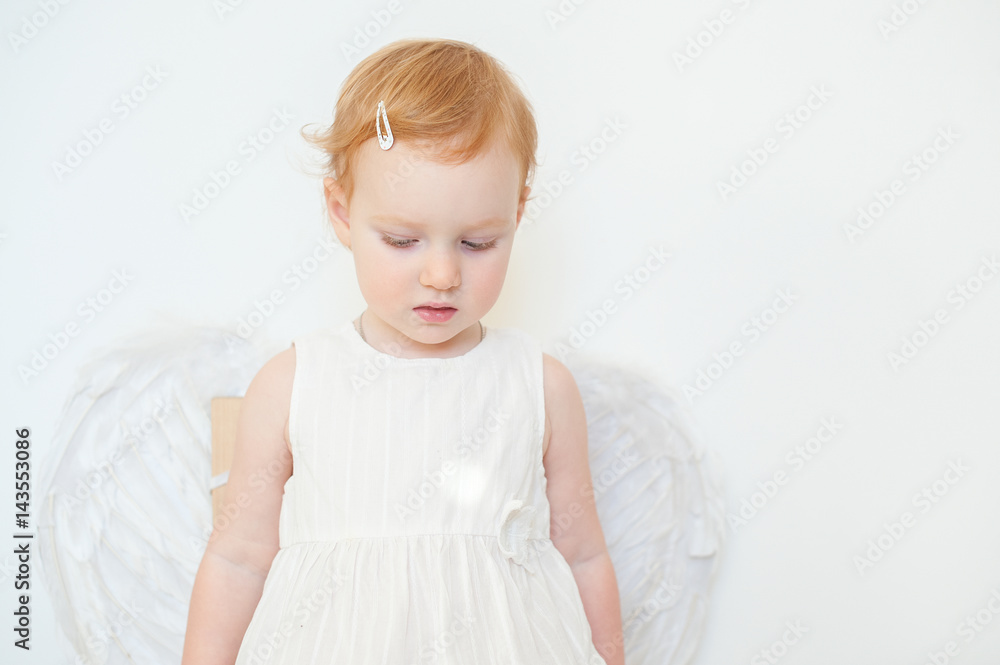 Red-haired angel girl on white wall background Red-haired angel girl on white wall background