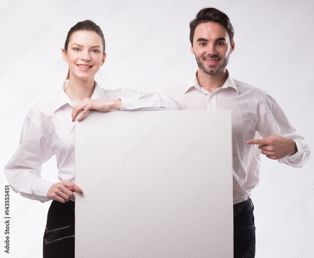 Young happy couple showing presentation pointing on placard over gray background Young happy couple showing presentation pointing on placard over gray background