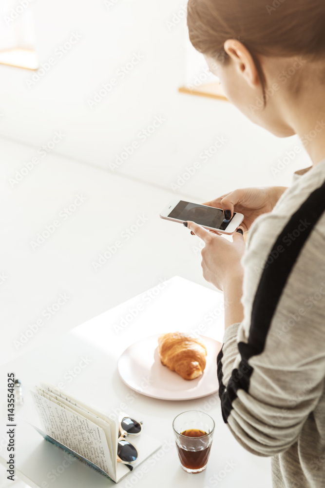 Vertical photo. Girl shooting trendy food pictures on phone.