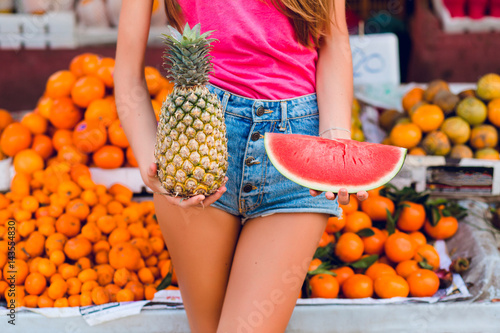 Ananas and slice of watermelon in hands of girl on tropical fruits background. photo
