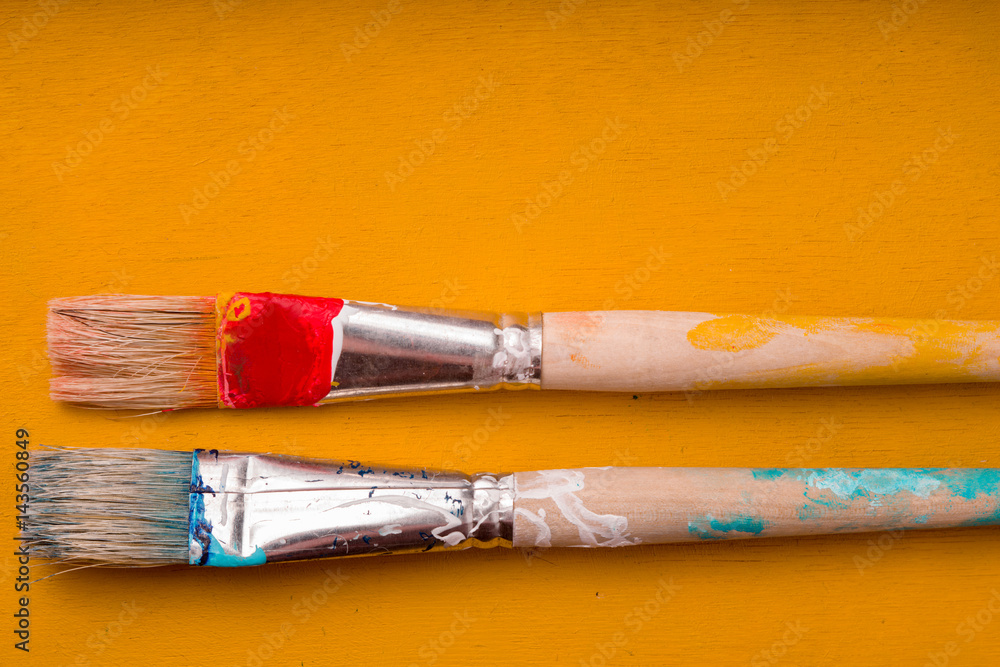 Fototapeta premium Paint brushes on the yellow background top view