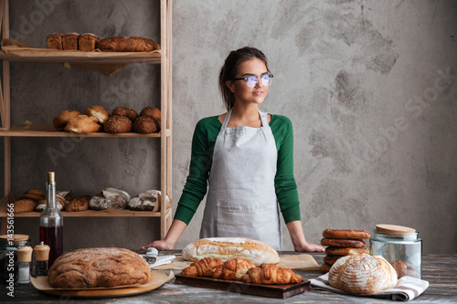 Amazing young lady baker standing at bakery near bread
