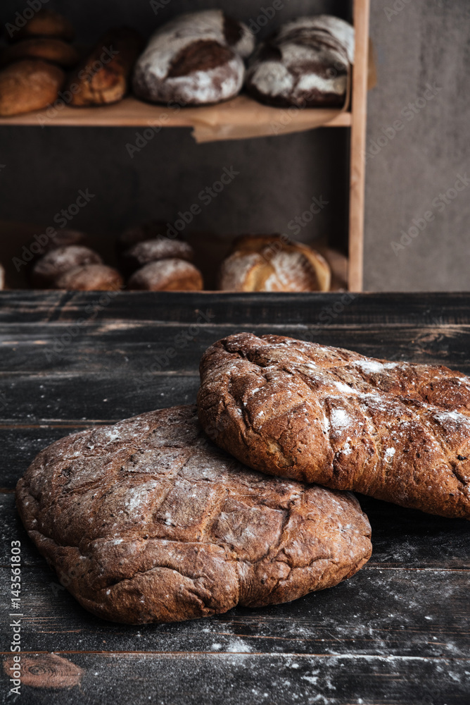 Bread with flour on dark wooden table at bakery