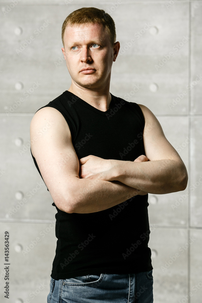 Obraz premium serious man on the background of concrete walls and metal pipes in a black shirt and jeans