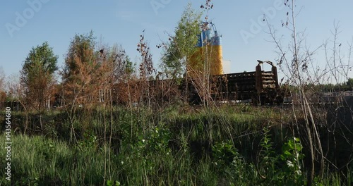 Oil Storage Reservoirs Painted in Yellow and Blue Colors, Sticking Out From Some Wooden Fence, in Ukraine, in the Daytime in Summer photo