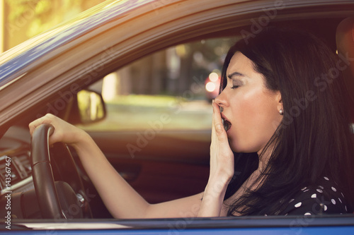 sleepy yawning woman driving her car after long hour trip.