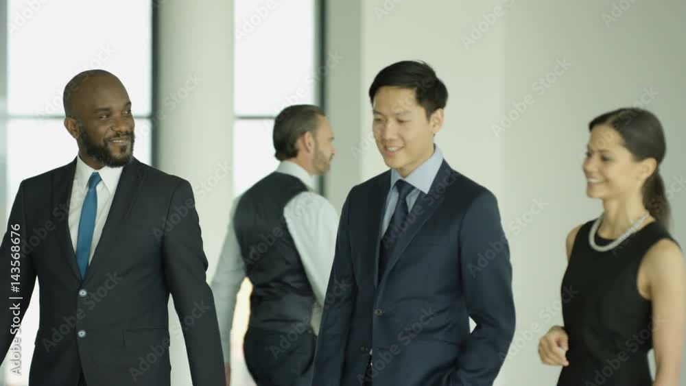 Cheerful business group chatting as they walk through busy modern office Cheerful business group chatting as they walk through busy modern office