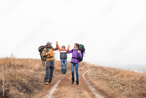 Happy family with backpacks holding hands