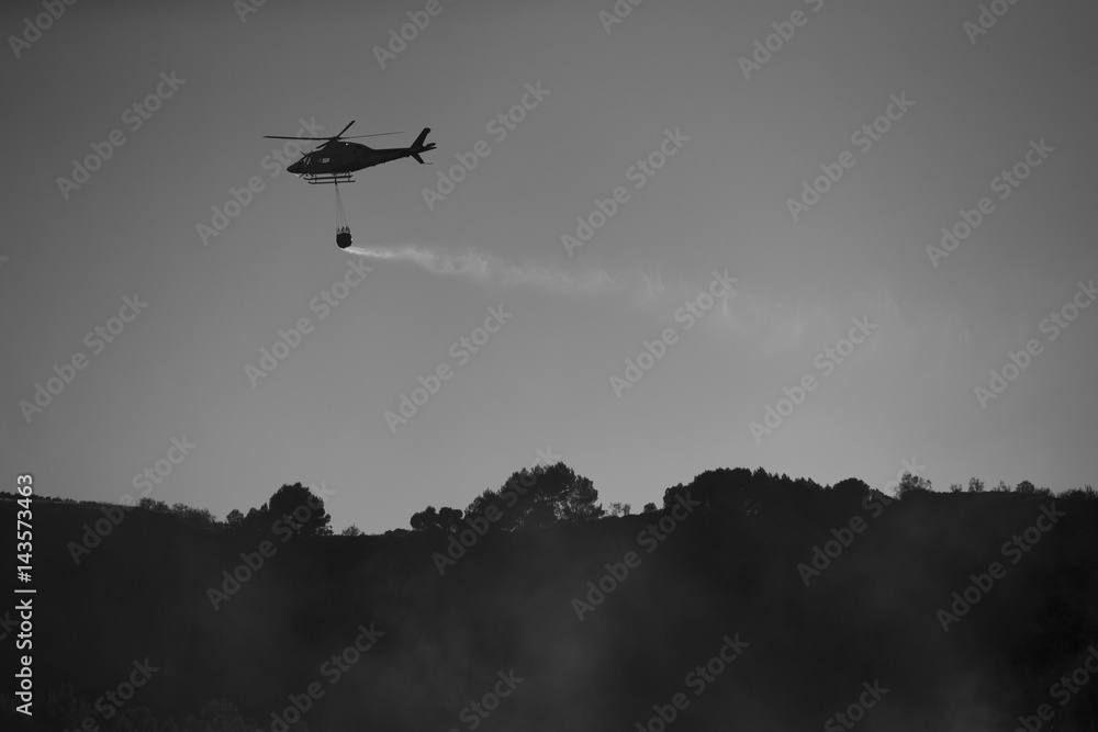 GRANADA, AUGUST 28: Fire fighting Helicopter, with bambi basket, during a fire fighting in the bush. August 28, 2014, Granada, Spain. GRANADA, AUGUST 28: Fire fighting Helicopter, with bambi basket, during a fire fighting in the bush. August 28, 2014, Granada, Spain.
