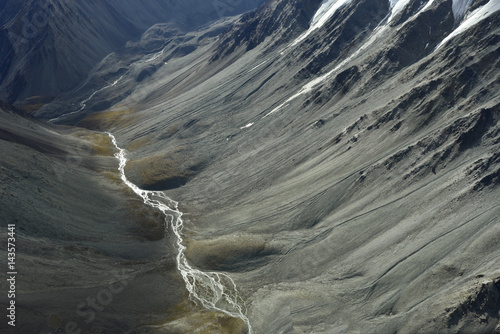 deep valley with a small creek between high mountains and a sunny spot