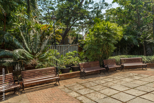 Wide view of group of unoccupied wooden seats or chairs arranged in a garden or park, Chennai, India, April 1st 2017