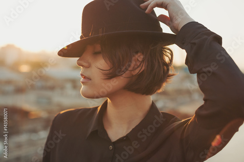 City style young woman with hat. Close up portrait. Urban sunset background. Dreaming mood.  photo