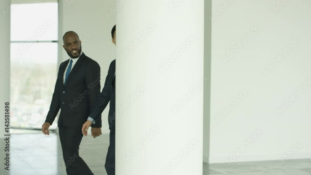 Cheerful business group chatting as they walk through busy modern office Cheerful business group chatting as they walk through busy modern office