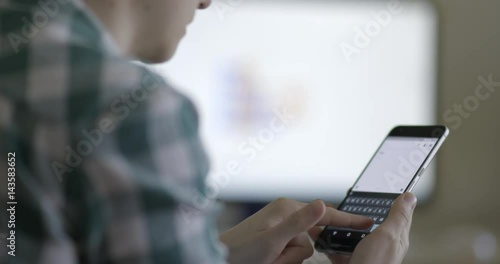 Young  woman text messaging on smartphone while sitting at the office