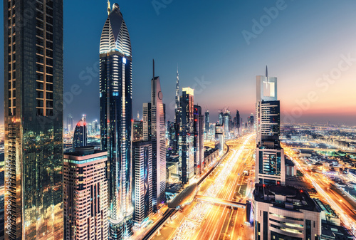 Spectacular nighttime skyline of Dubai, UAE. Futuristic architecture of a big city at night. View over the famous highway with illuminated skyscrapers. Colourful travel background.