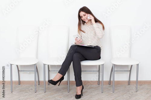 pretty girl talking on her cell phone sitting on a white chair.