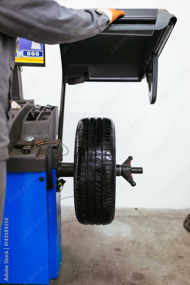 Fototapeta premium Auto mechanic repairing car. Selective focus on wheel.