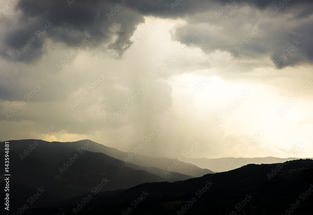 Rain clouds and strange yellowish light over the hills of the Apennine Mountains