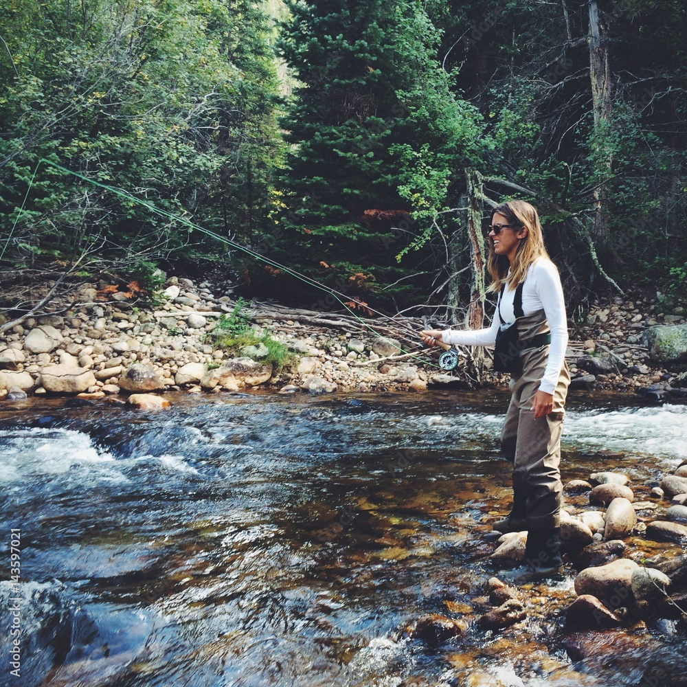 Young woman fly fishing along a Colorado stream Stock Photo