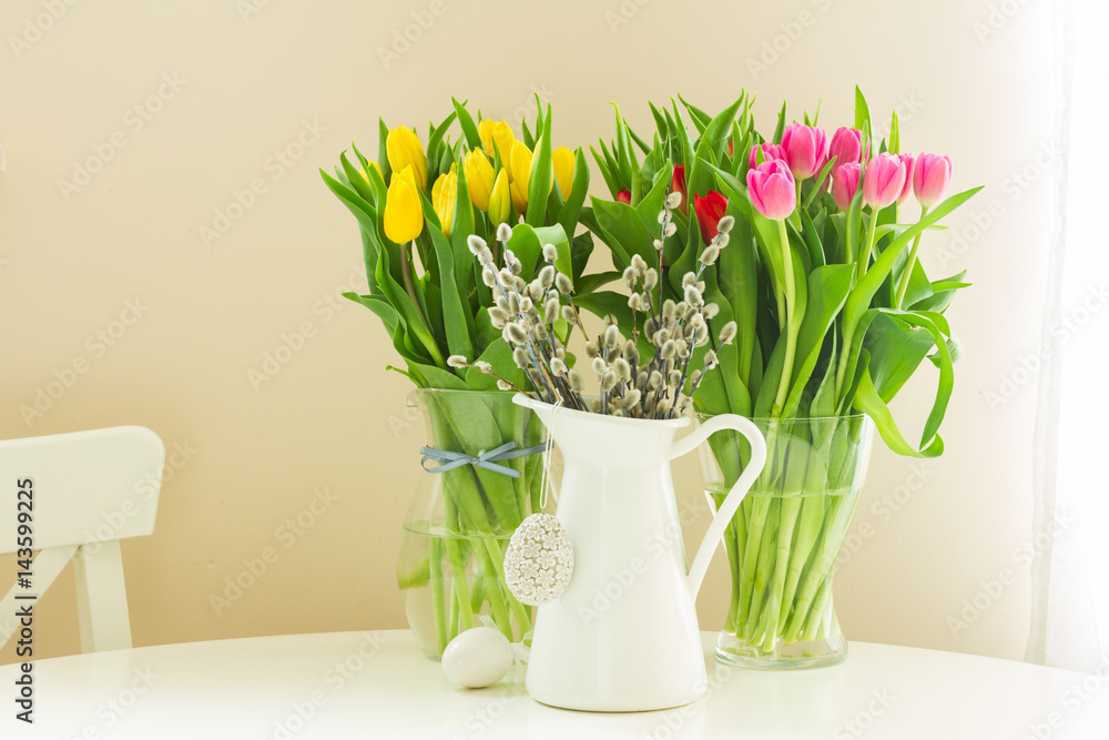 fresh yellow and violet tulips and willow catkins in pot with easter eggs