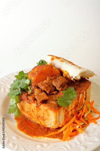 Closeup of lamb "bunny chow" - the popular, Indian fast food cuisine which originated in South Africa, with carrot salad