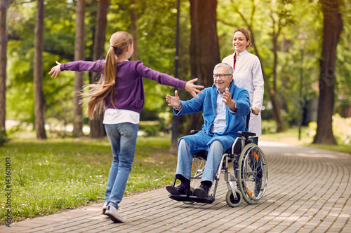 cheerful grandchildren visiting disabled father in park. photo