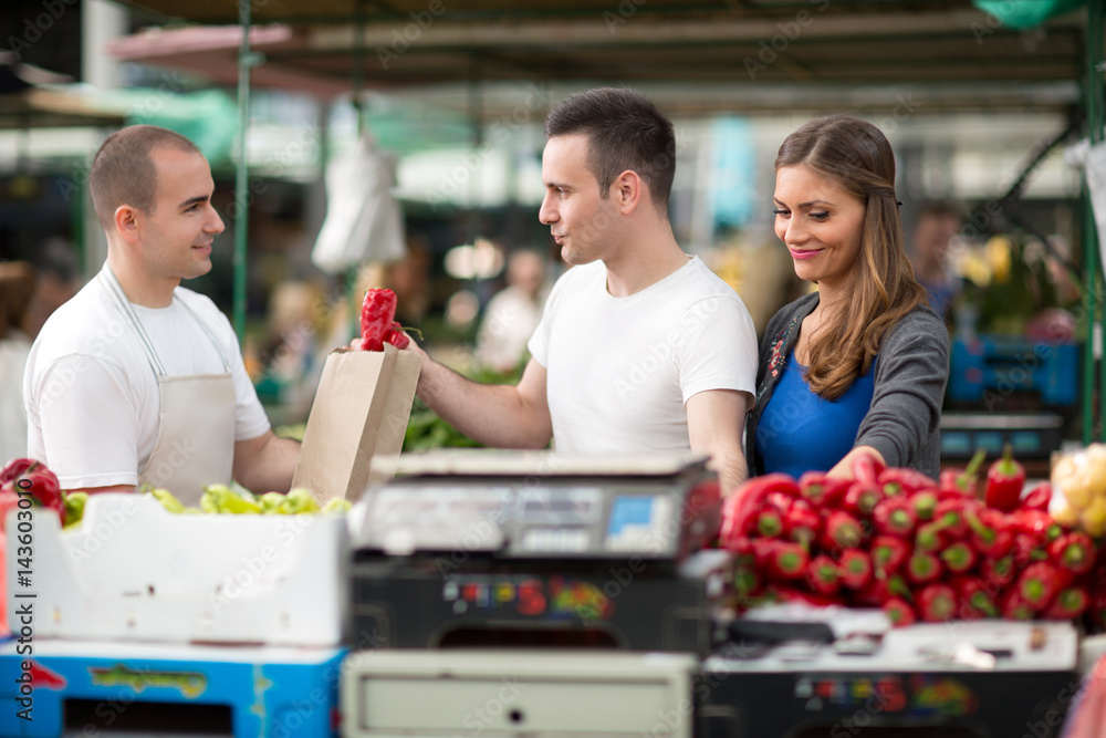 customer picking pepper from salesman at street market.