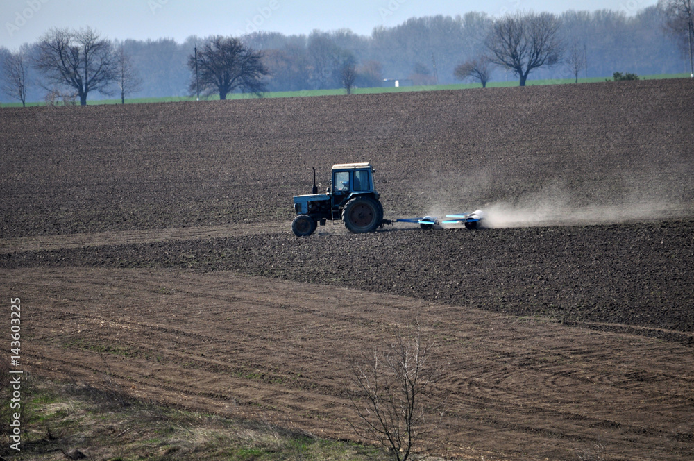 Fototapeta premium Track rollers with tractor prepares soil for planting spring crops