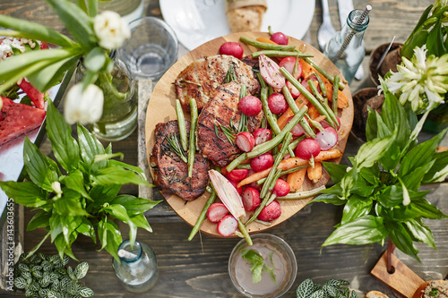 grilled meat with vegetables served on the round wooden coaster photo