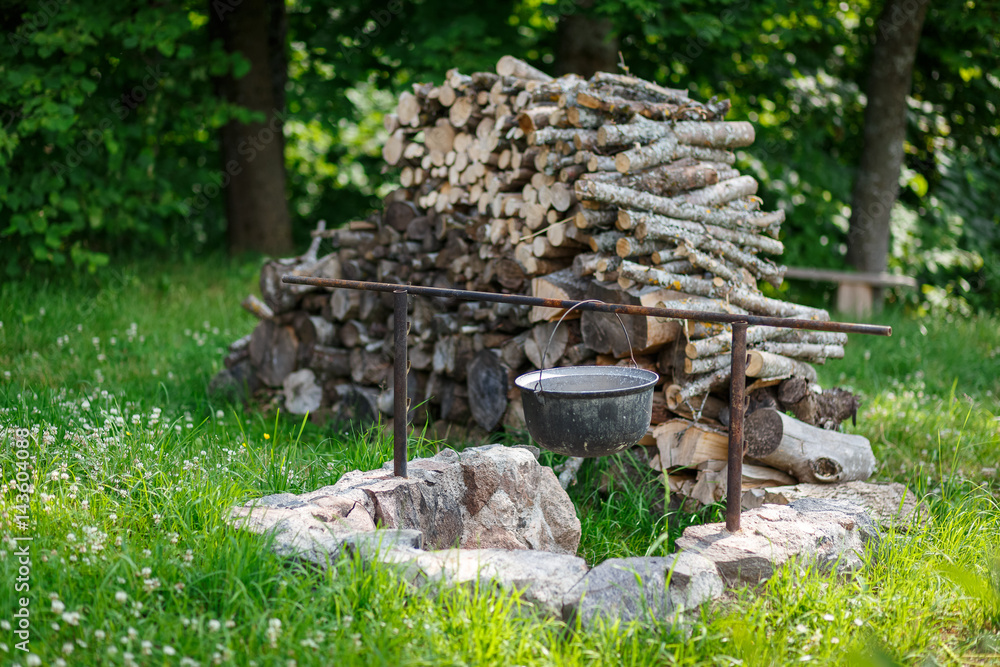 a cauldron and a pile of firewoods on the lawn a cauldron and a pile of firewoods on the lawn