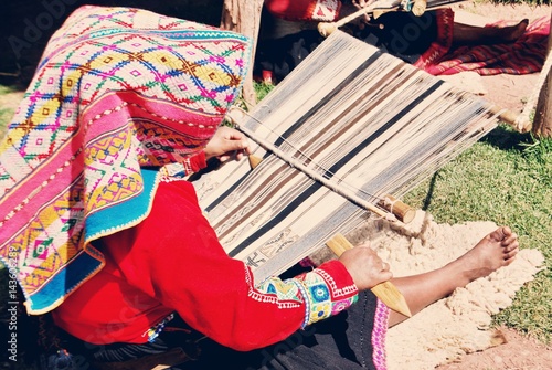 Peruvian woman sitting and weaving colorful textiles