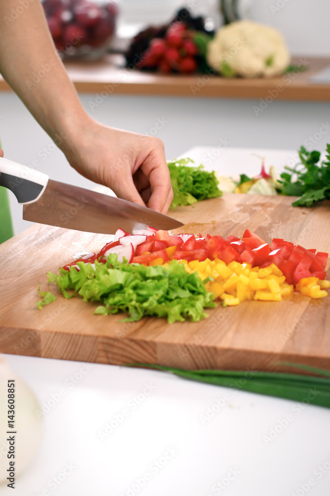 Close up of  woman's hands cooking in the kitchen. Housewife slicing ​​fresh salad. Vegetarian and healthily cooking concept