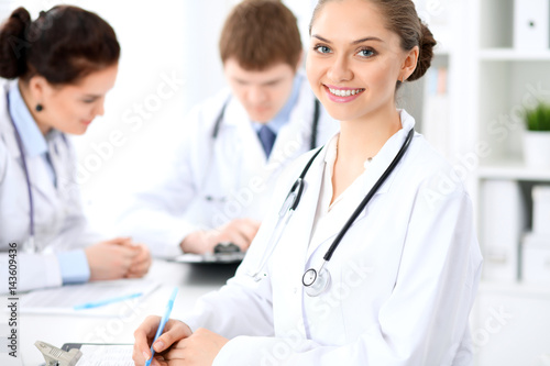 Happy female doctor with medical staff while sitting at the table.  Successful team at health care and medicine concept