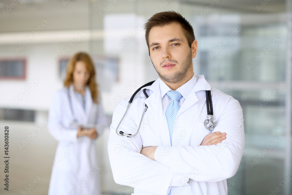 Smiling doctor waiting for his team while standing upright Smiling doctor waiting for his team while standing upright