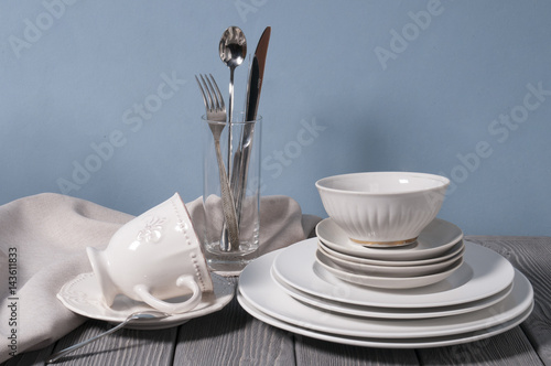 Minimalistic still life: set of rustic gray wooden tableware on blue background. Soft light, high key. photo