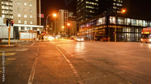 Linear timelapse moving up at a busy intersection at night with traffic and people crossing in Ghandi Square, mid city Johannesburg, South Africa