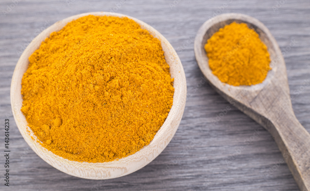 Turmeric powder in the wooden bowl (Curcuma longa) Turmeric powder in the wooden bowl (Curcuma longa)