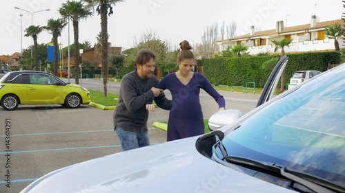 Husband helping pregnant woman to enter car