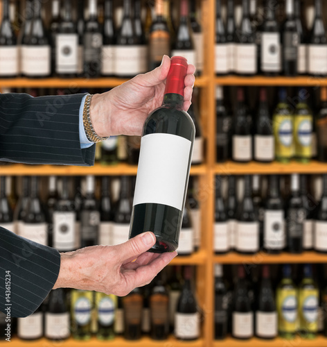 Sommelier offering bottle of red wine to customer