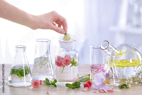 Woman mixing perfume samples on table