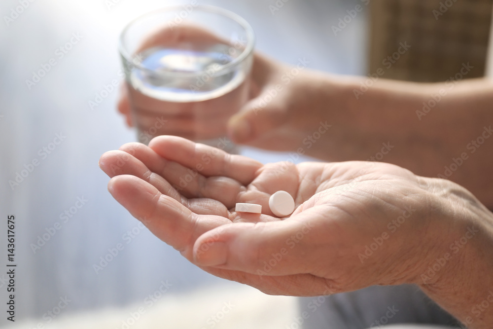 Senior woman with pills and glass of water at home, closeup Senior woman with pills and glass of water at home, closeup