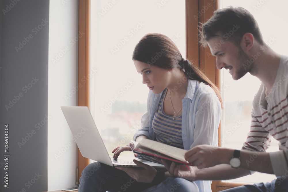 Young couple sitting on the floor and looking at the blueprint of new home Young couple sitting on the floor and looking at the blueprint of new home