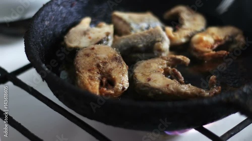 Fish fried in a pan turned with a fork photo