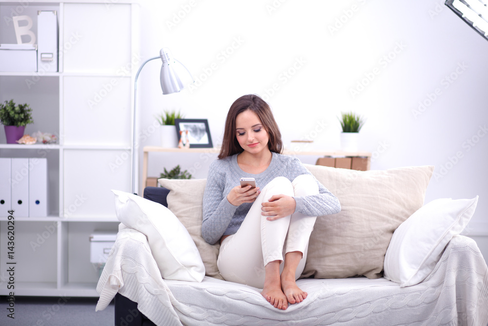Pretty girl using her smartphone on couch at home in the living room Pretty girl using her smartphone on couch at home in the living room