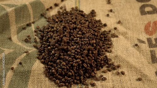 Dropping coffee bean on burlap. Closeup of coffee beans. Slow motion