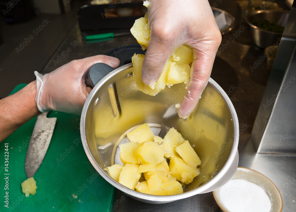 Close up shot of a hand dropping fluffy peeled potatoes into a blender. Close up shot of a hand dropping fluffy peeled potatoes into a blender.