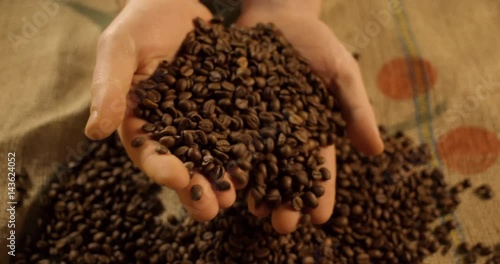 Adult man hands holding coffee grains. Close-up. Slow motion.