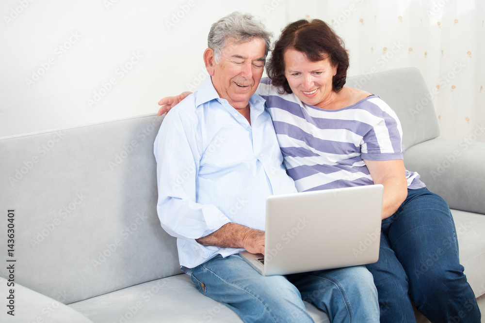 Senior couple laughing while using laptop Senior couple laughing while using laptop